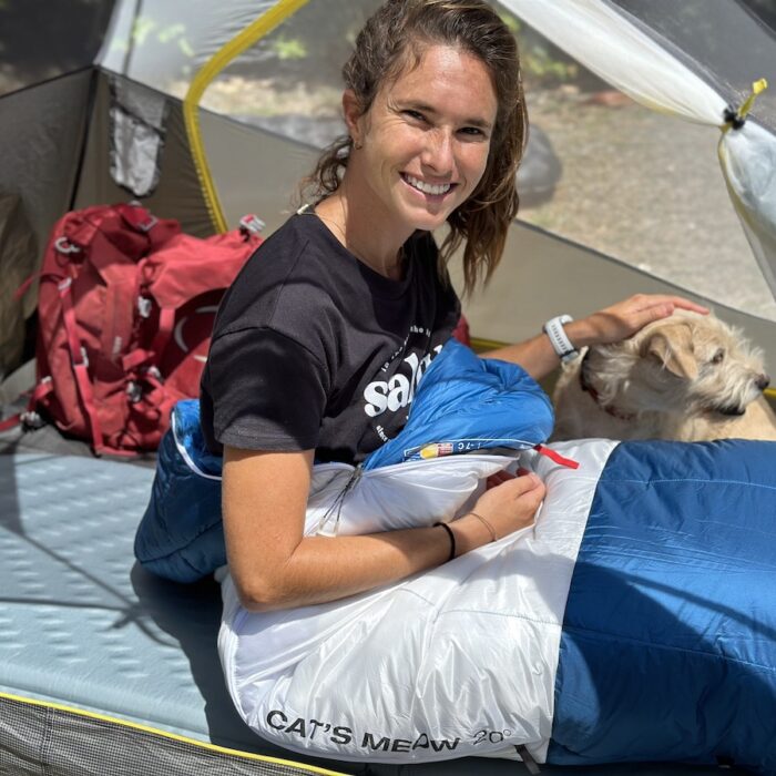 a woman sitting in a sleeping bag in a tent