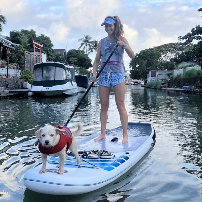 a woman stand up paddling with her dog