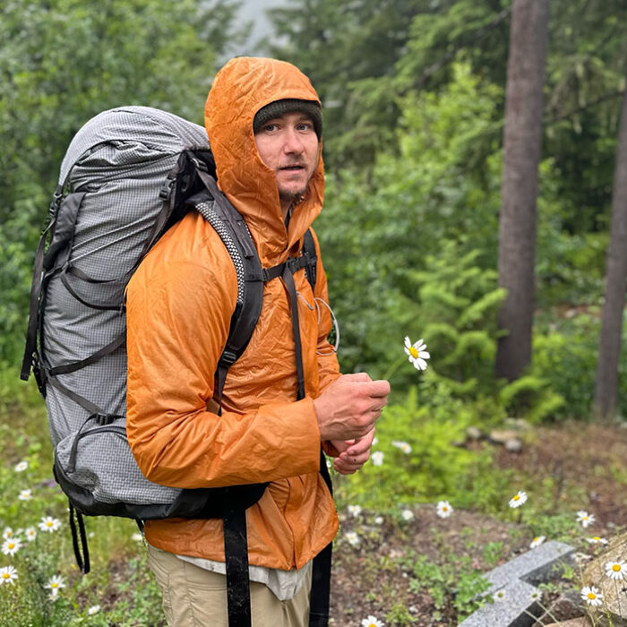 a hiker with a backpack holding a flower