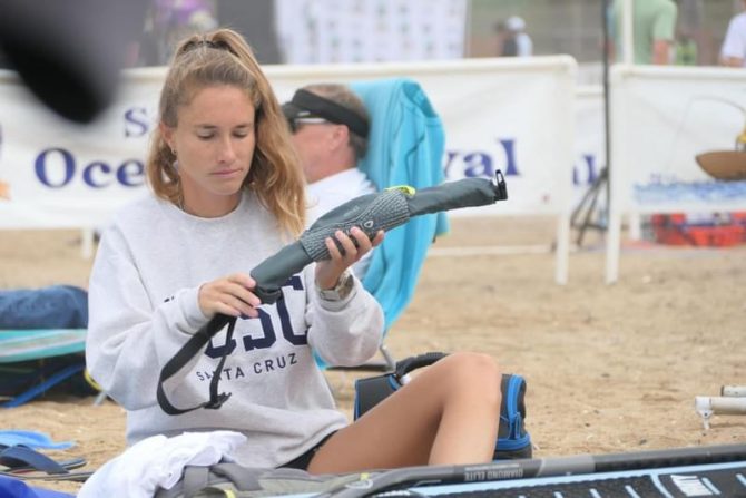 a woman sitting on the beach holding a PFD