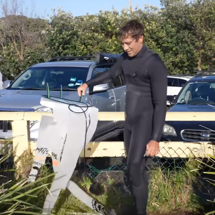 Koa Rothman holding the flayed remains of his surfboard. Photo: Koa Rothman // YouTube