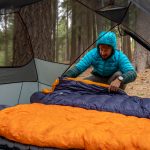man setting up backpacking sleeping bags in tent