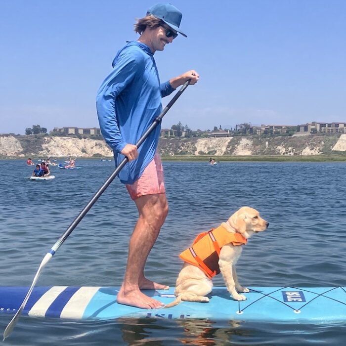 a man on a paddle board with a dog