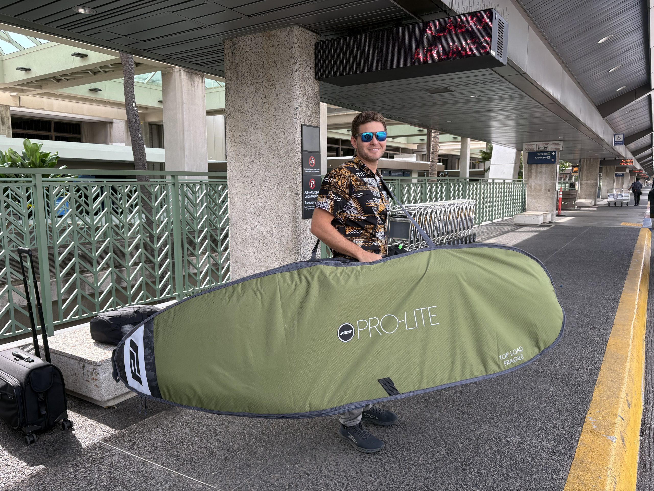 a man at the airport with a surfboard bag