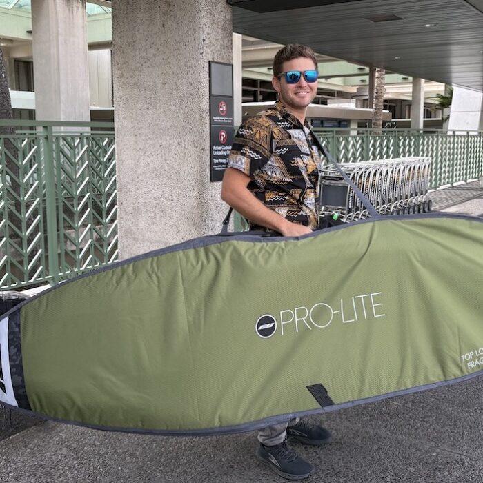 a man holding a surfboard bag at the airport