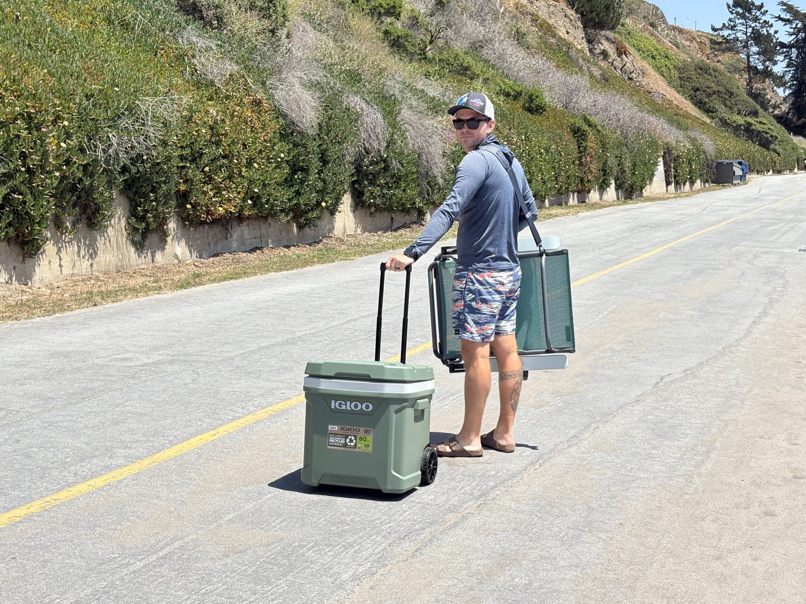 a man rolling a cooler at the beach