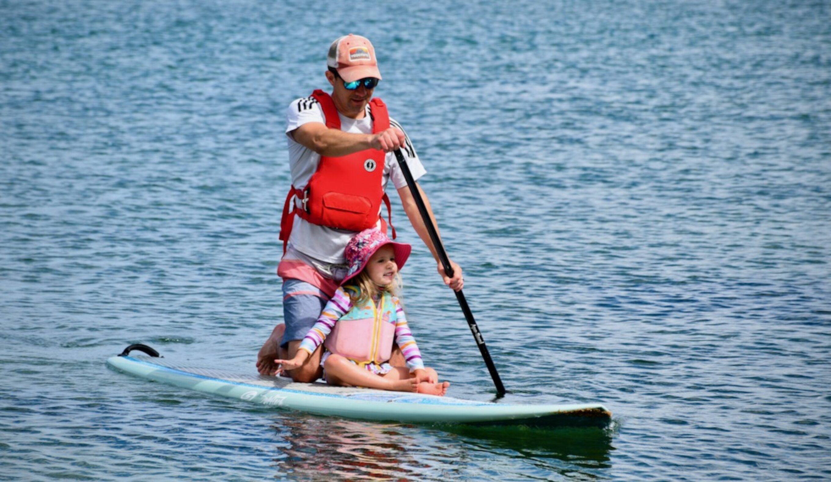 A man and his daughter paddling on a paddle board
