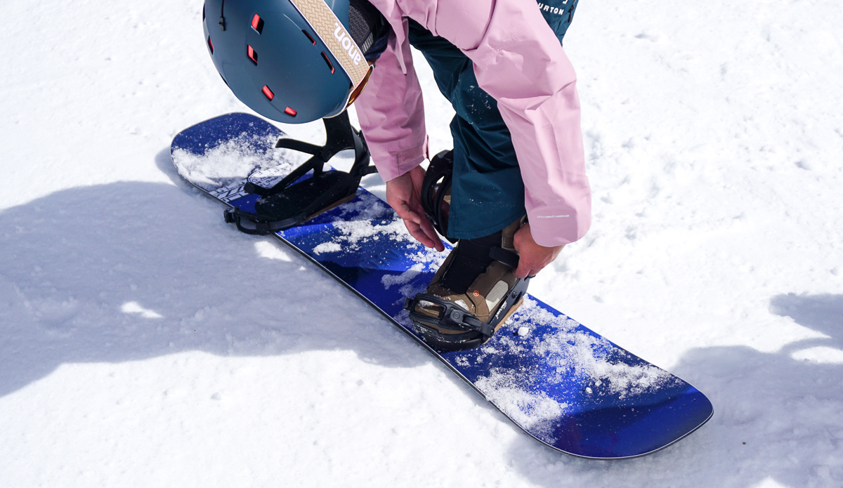 man strapping snowboard bindings
