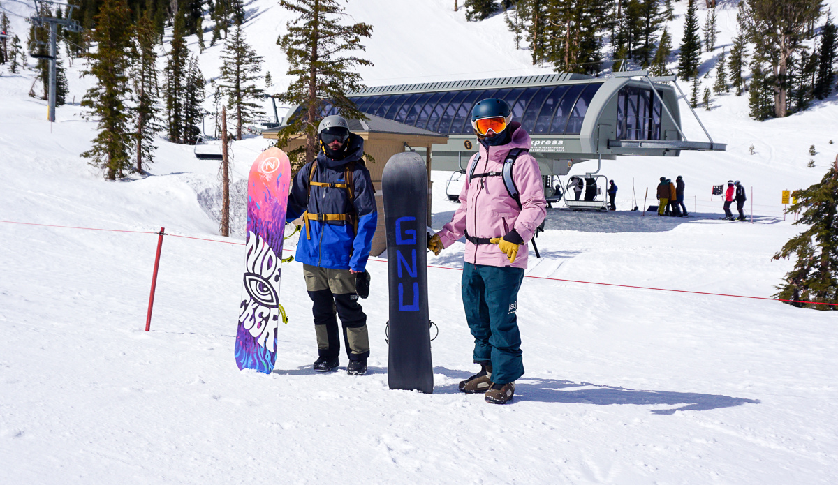 two men holding snowboards near a lift