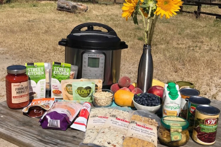 An outdoor meal prep display with a pressure cooker and different kinds of meal prep foods