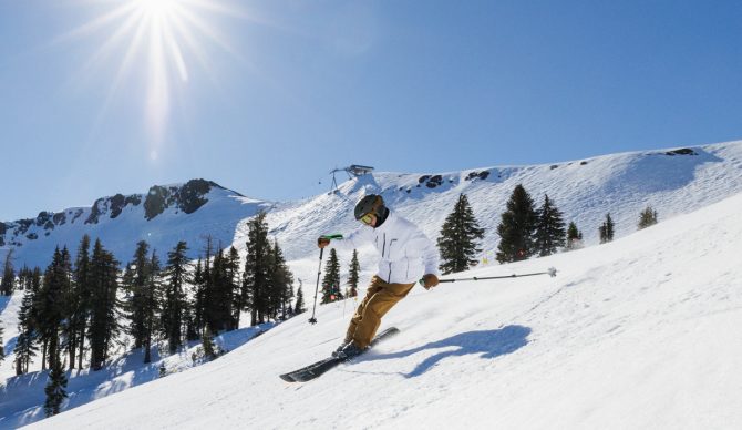 skiing in the HH Alpha 4.0 ski jacket and flylow baker bibs