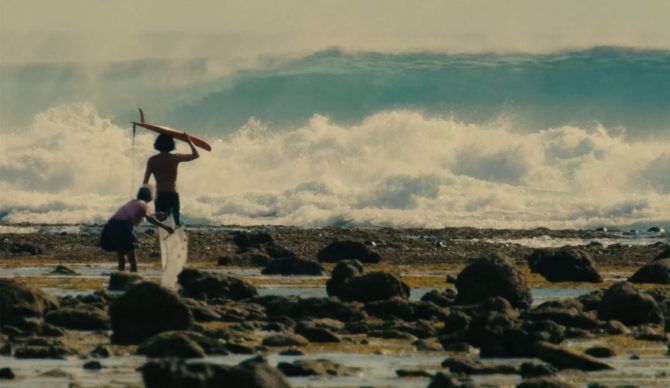 Craig Anderson with surfboard walking towards a wave for Samudra Spirit Glitters.