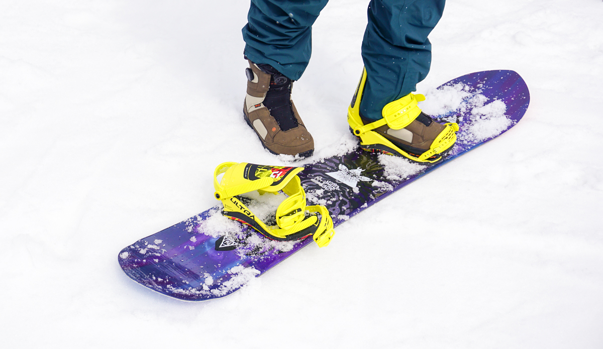 man standing with one foot on snowboard