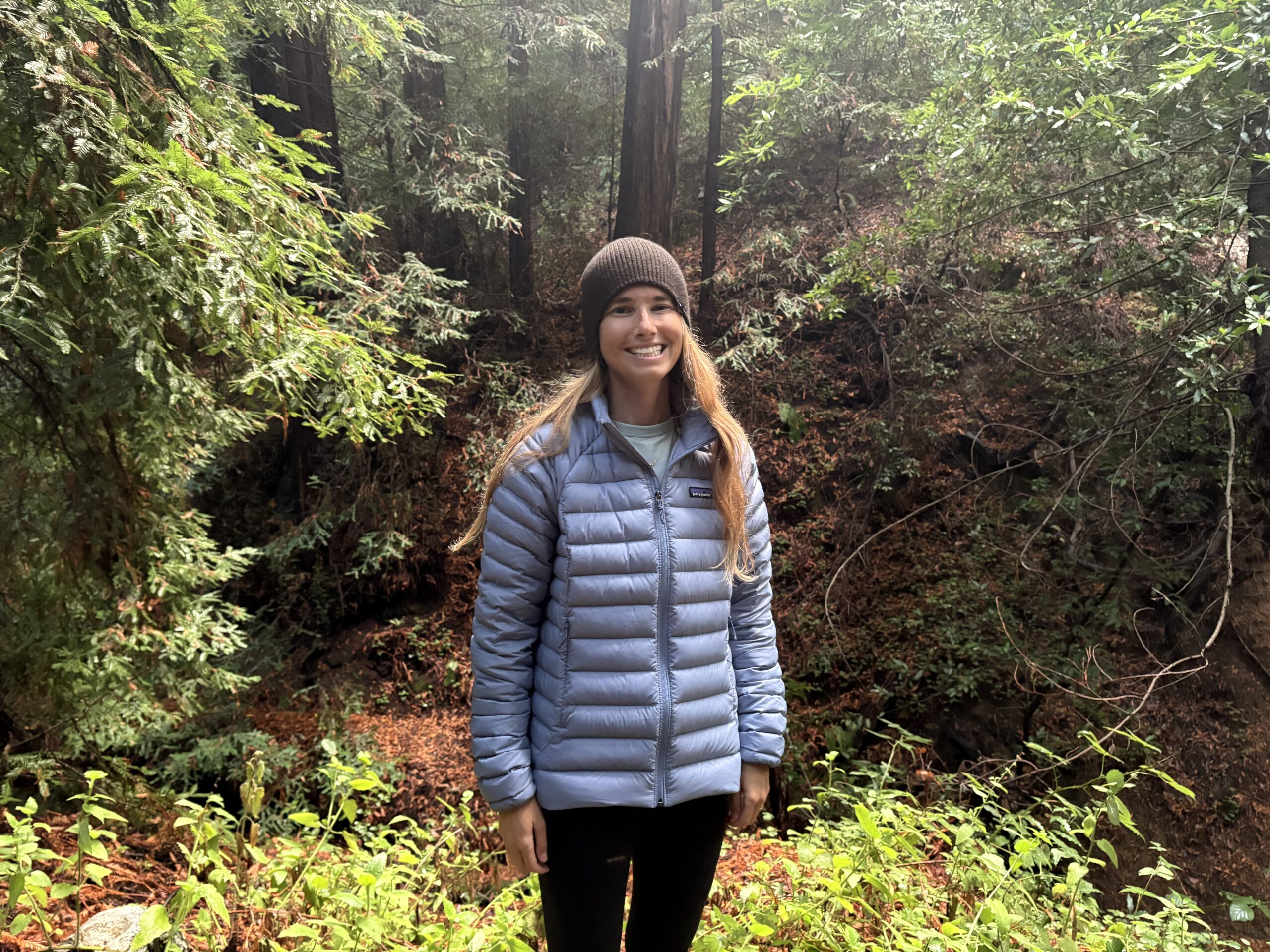 a woman in the forest wearing a puffer jacket