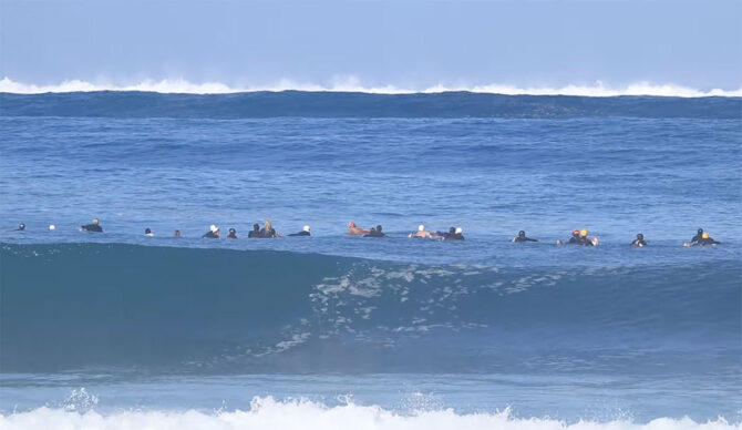 Pipeline surfers paddling towards incoming waves