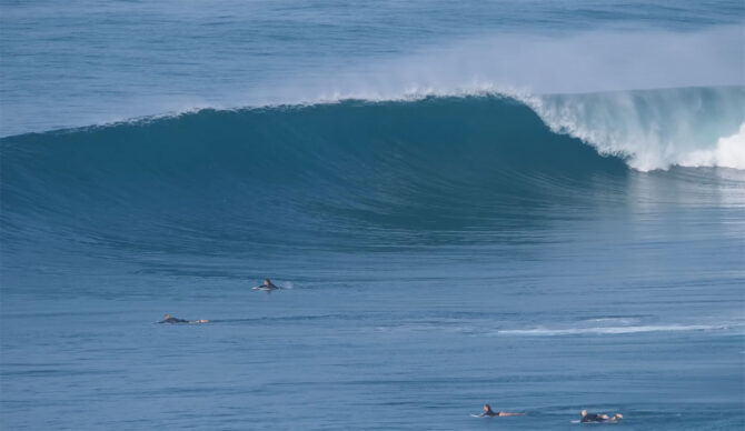 Indonesia wave breaking with surfers paddling towards it