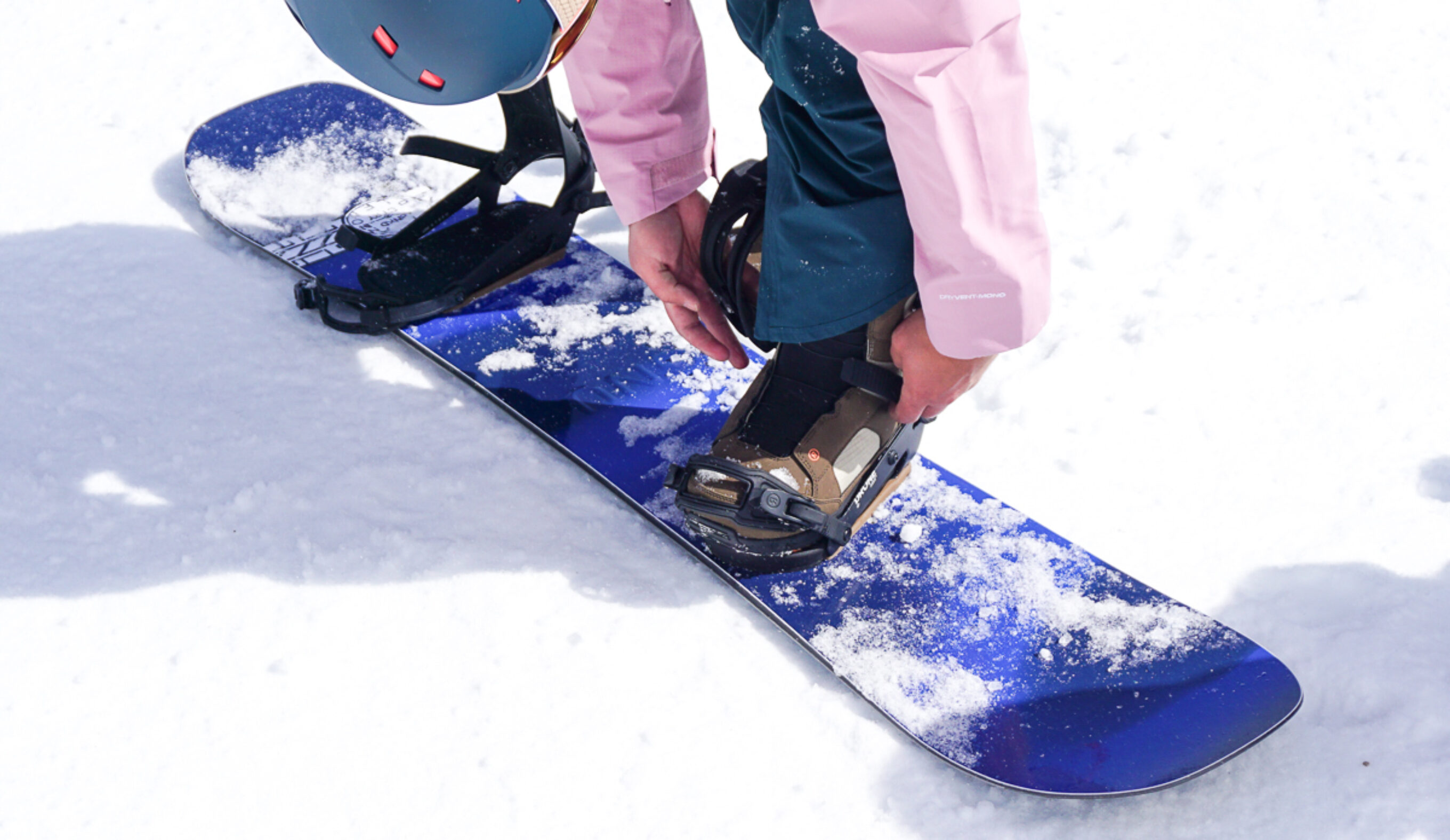 man strapping in to GNU Banked Country Snowboard