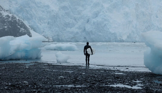 Ben Gravy standing with a surfboard in Alaska