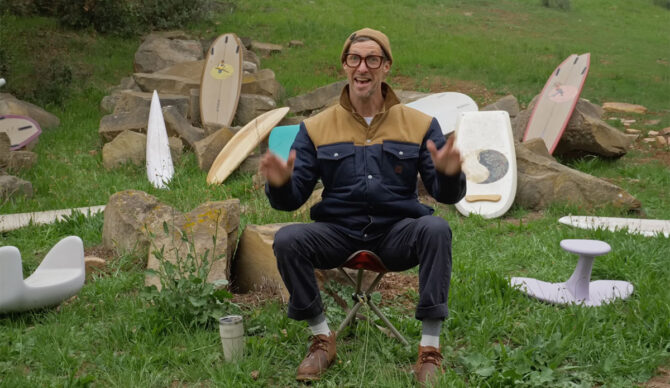 Donald Brink sitting in front of surfboards he made