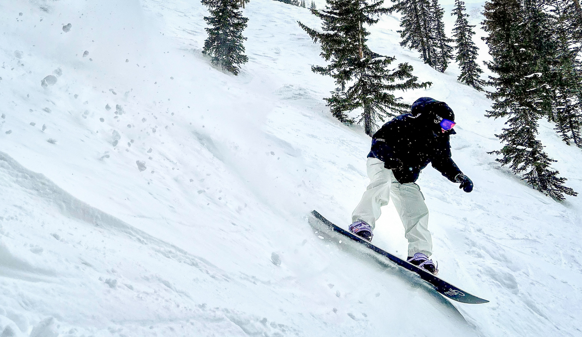 woman snowboarding treeline