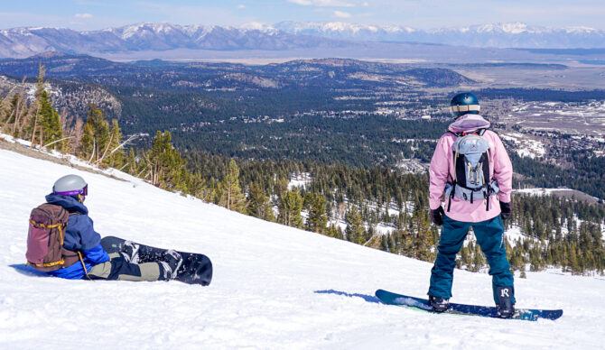two snowboarders looking at mountain view