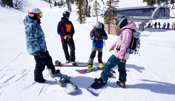 four people comparing snowboards