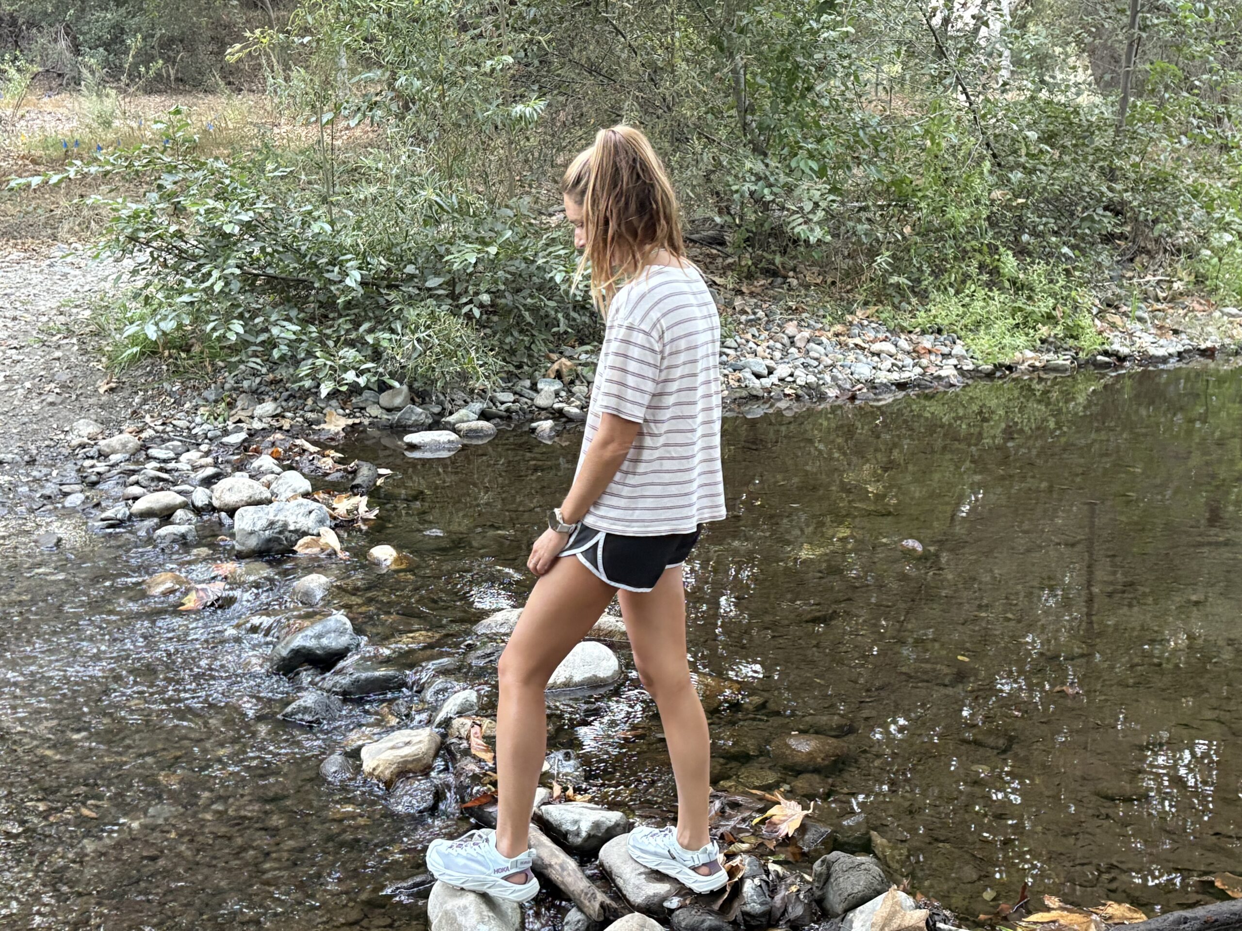 a woman crossing a creek