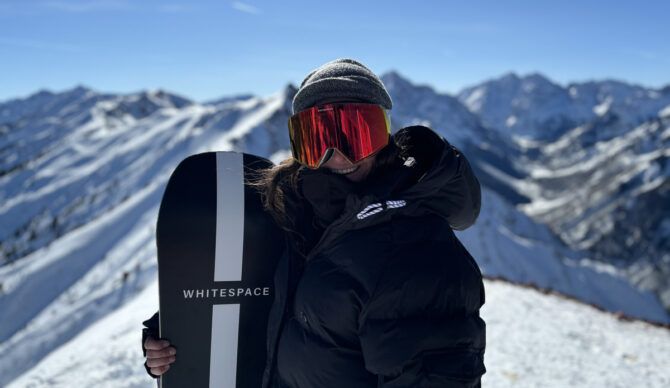 woman with snowboard on mountain top
