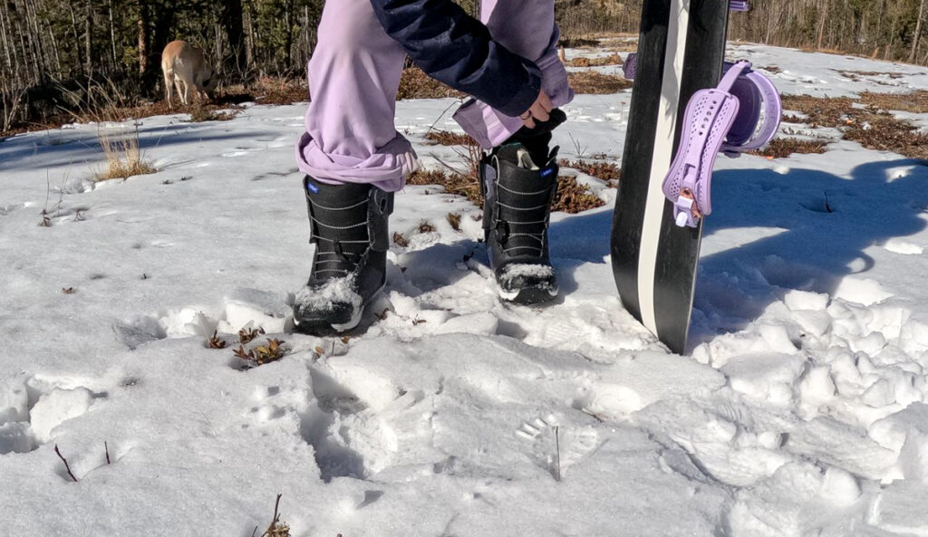 woman adjusting snowboard boots