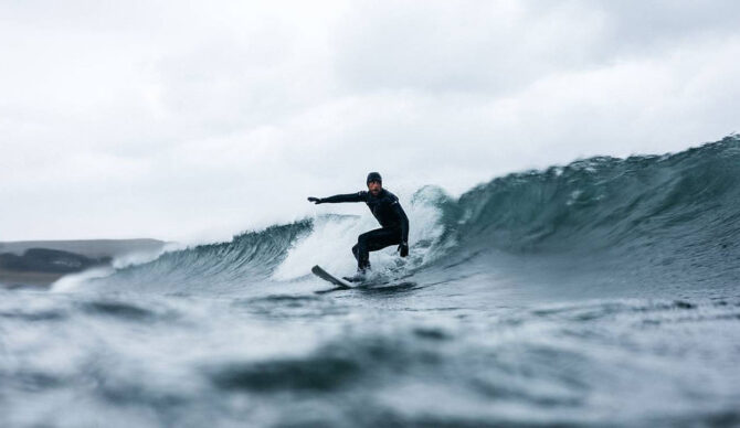 Surfer wearing a Finisterre wetsuit in the water