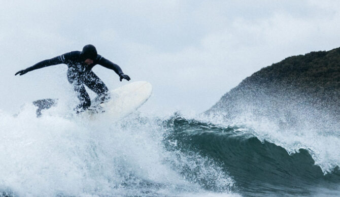 Surfer riding a wave in a Finisterre wetsuit