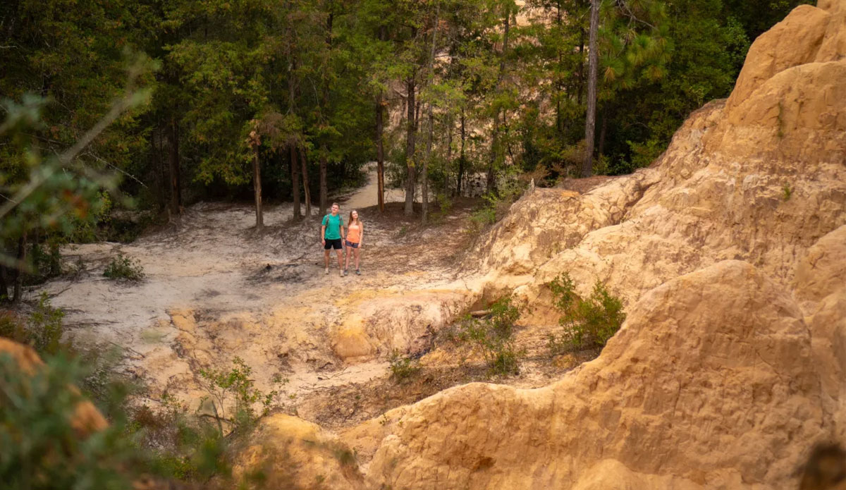 Red Clay Cliffs - Hiking - Long shot of couple looking at cliffs - 2023